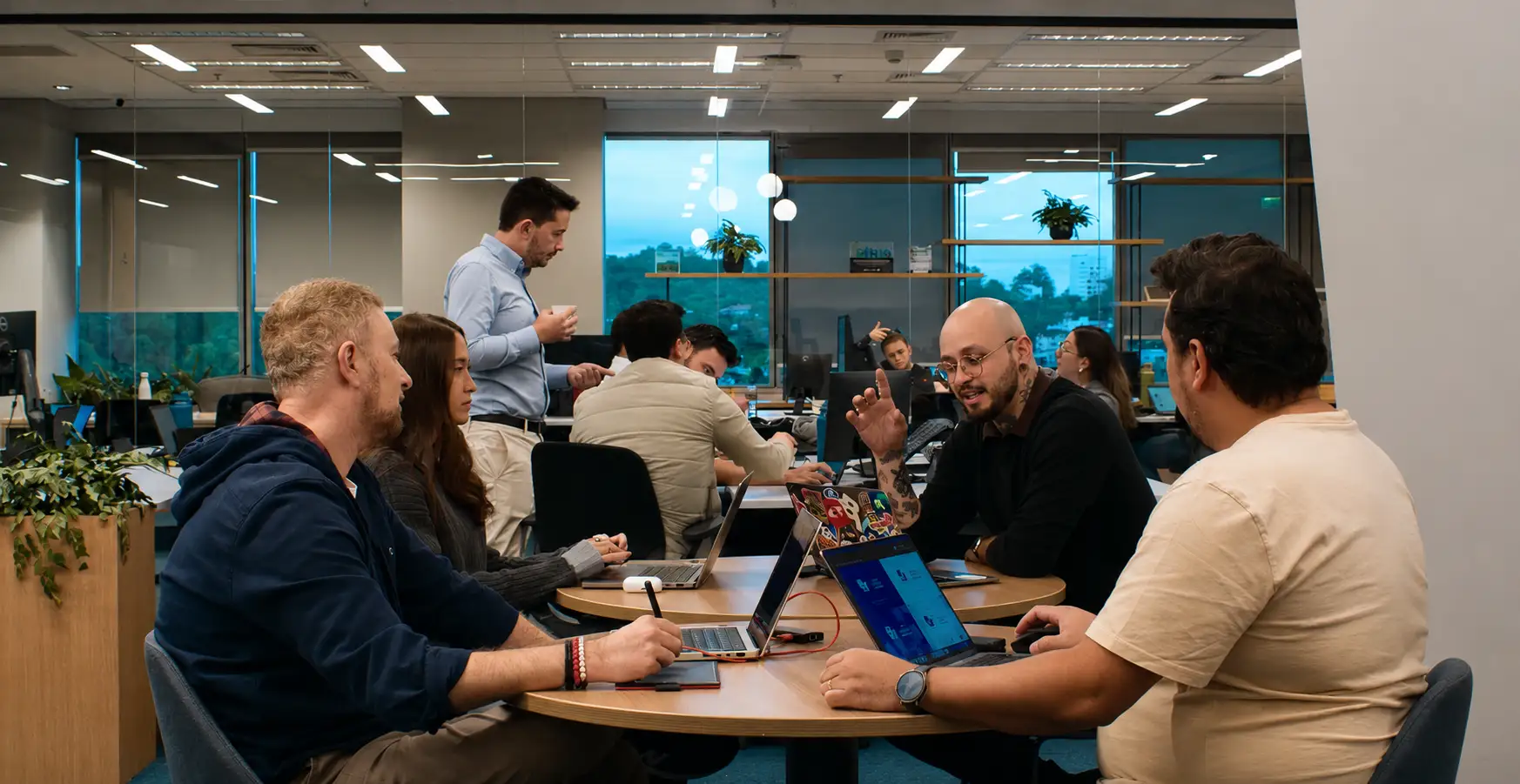 Equipo reunido en una mesa de trabajo colaborativo con notebooks abiertos, en una oficina moderna