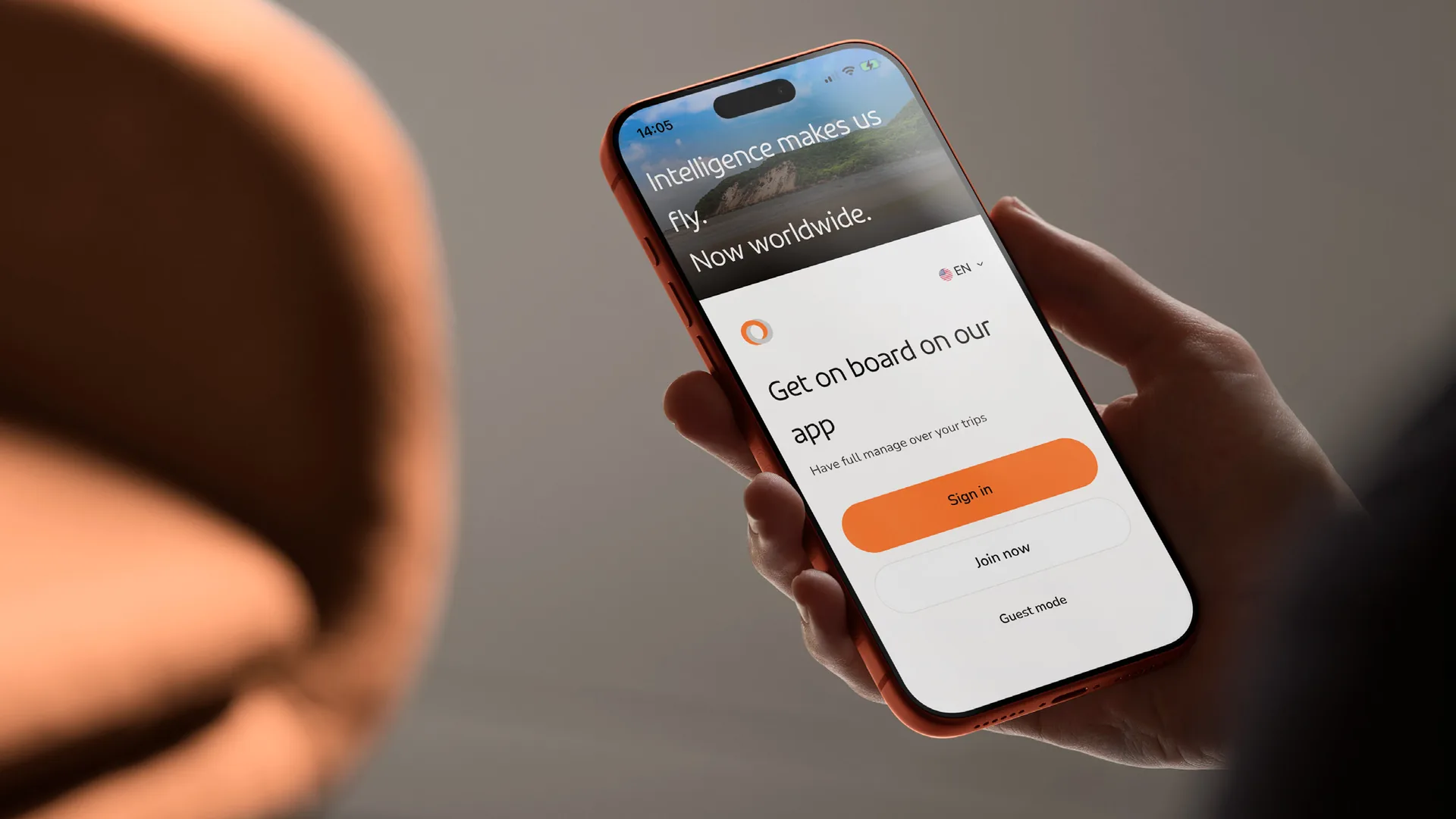 Mão segurando o celular com a tela de boas-vindas do app da GOL em inglês: “Intelligence makes us fly. Now worldwide.”