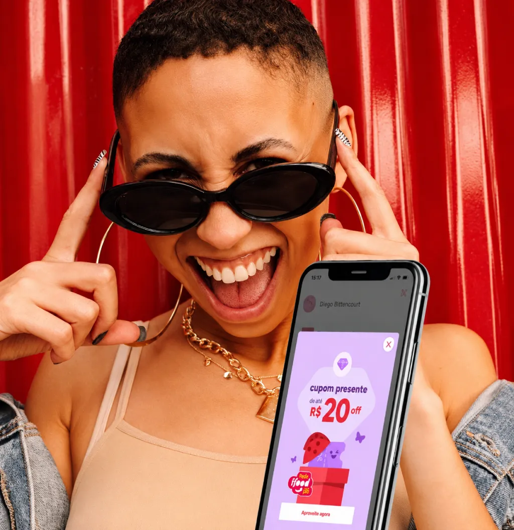 Smiling woman holding a phone with an iFood discount coupon on the screen