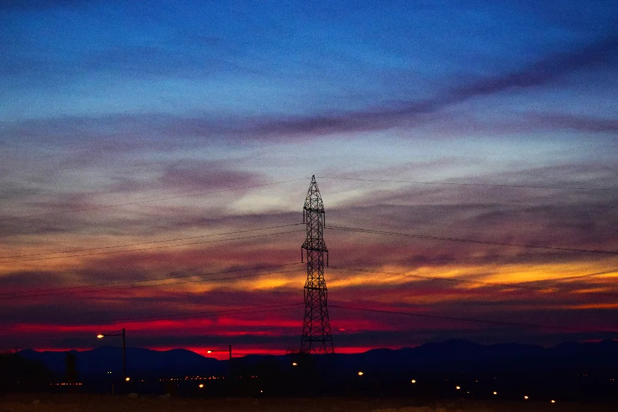 Torre de transmisión de energía al atardecer, representando el sector de telecomunicaciones